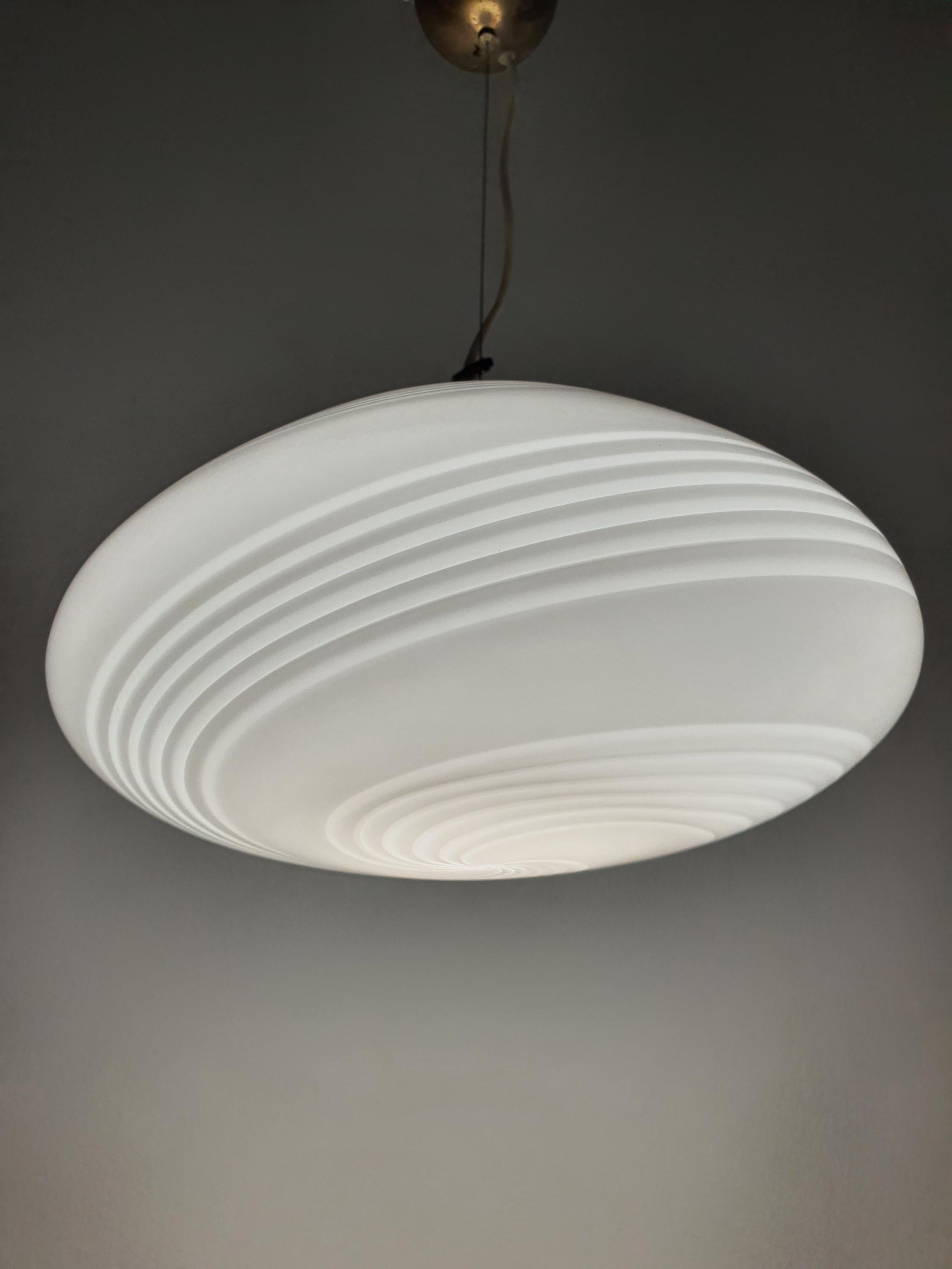 Vintage Murano white swirl oblate globe pendant lit, warm inviting glow through white swirl glass, dining room setting