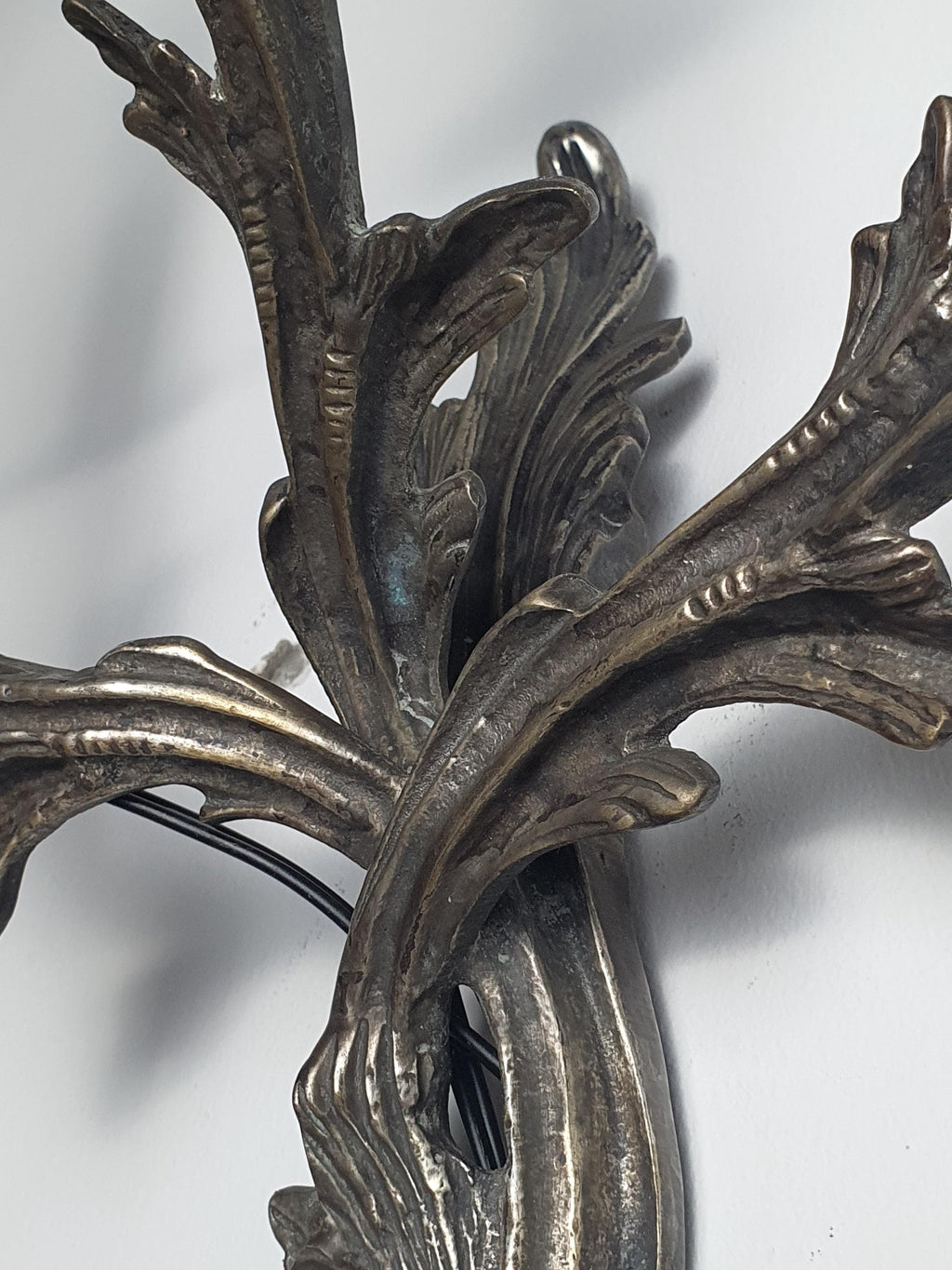 Gothic wall sconce — three candle-style arms extending from dark grey metal frame, detail