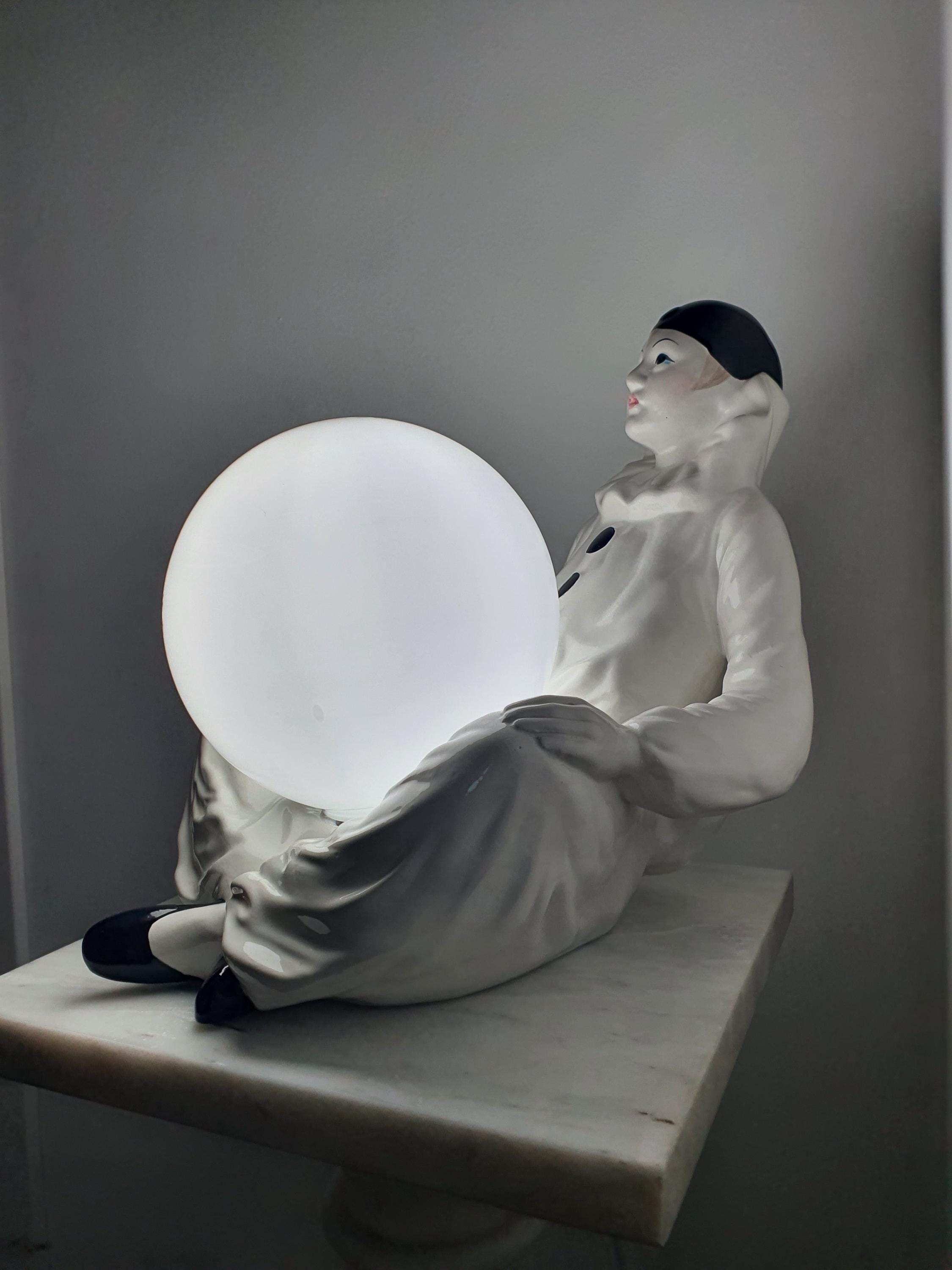 Vintage Italian Pierrot clown ceramic lamp in creative studio, theatrical figurine lamp, white globe, maximalist eclectic decor