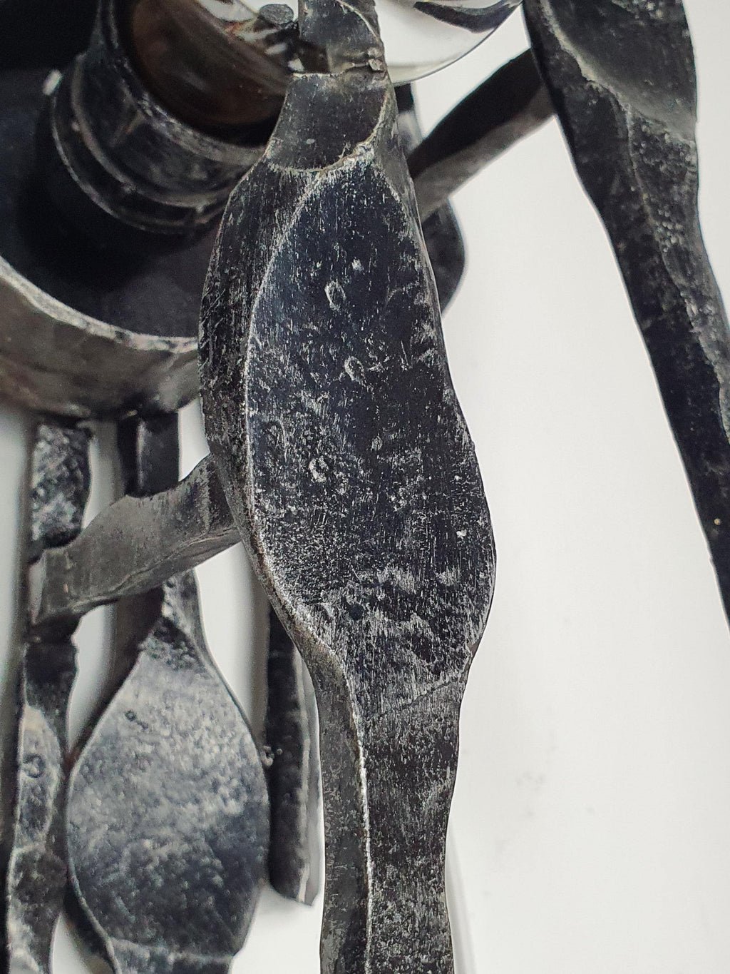 Detail of age-related patina and surface wear on vintage Brutalist wrought iron sconce