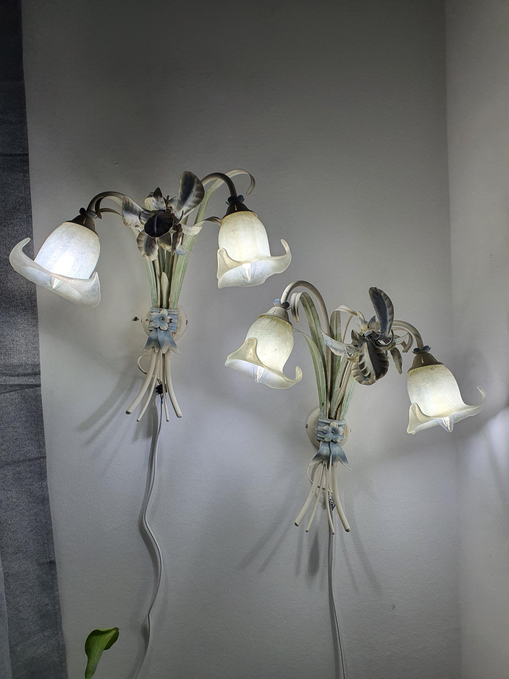 Vintage Italian toleware sconce — illuminated, warm ambient glow through floral metal composition