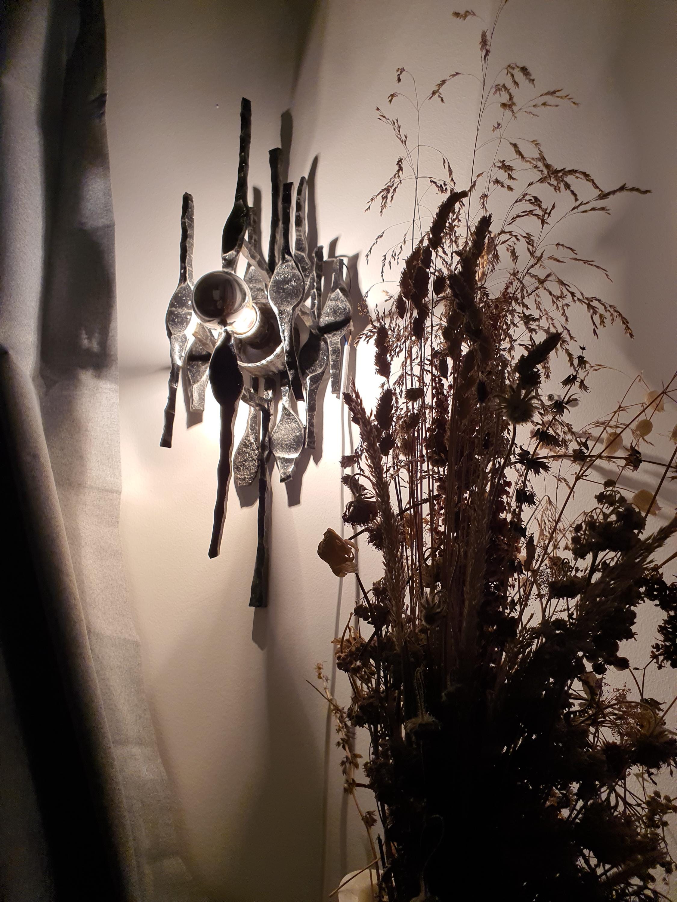 Vintage Belgian Brutalist wall sconce lit, dramatic shadows on wall, atmospheric glow