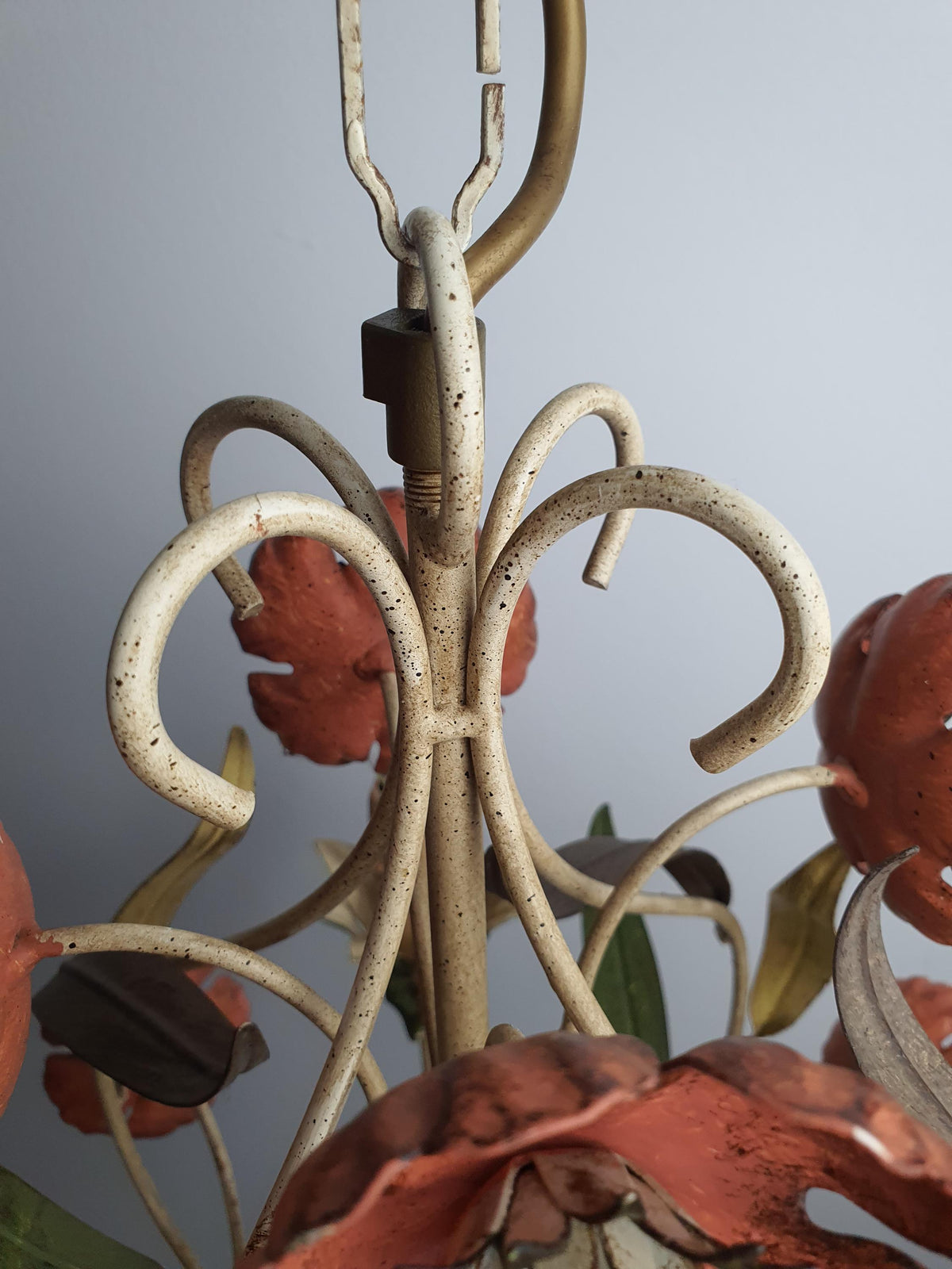 Close-up of paint wear and patina on vintage Italian tole chandelier arm, authentic decades-old vintage character