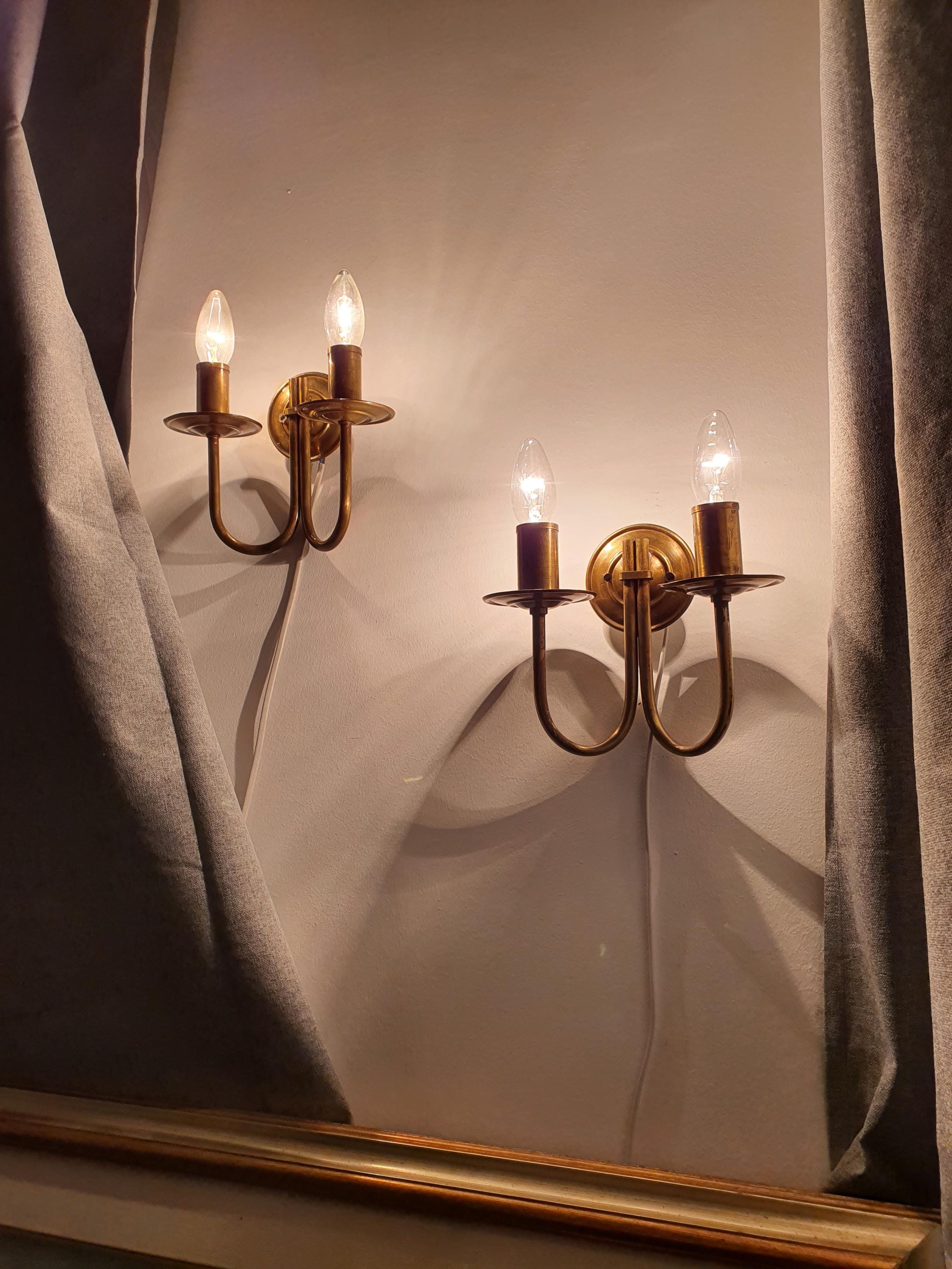 Pair of vintage Italian double-arm lacquered brass wall sconces framing bathroom mirror, symmetrical pair, Hollywood Regency