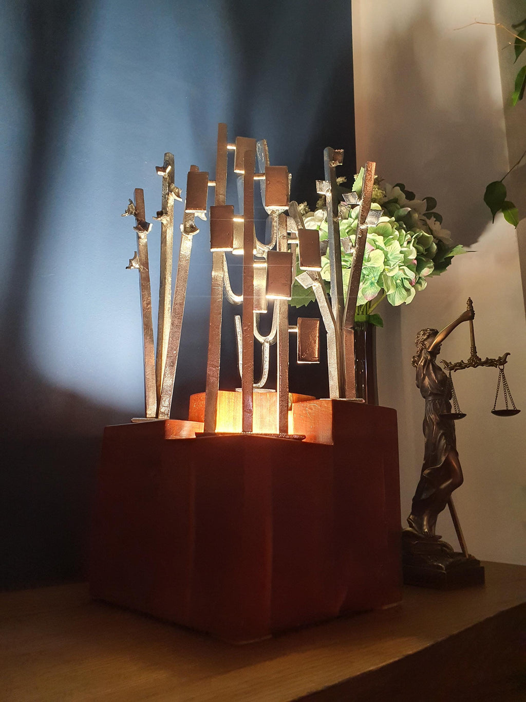 Signed Carlo Brutalist tree lamp lit, dramatic shadows through aluminium grove sculpture, warm wood base glow