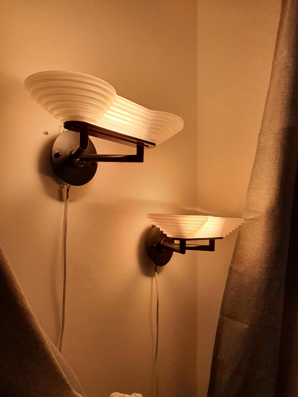 Pair of vintage Italian Memphis Postmodern wall lights lit, soft satin glass diffused glow, stepped pyramid form, dramatic shadows